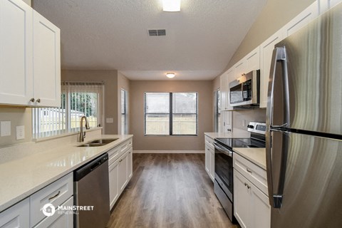 a kitchen with white cabinets and stainless steel appliances