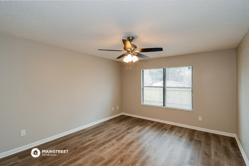 the spacious living room with hardwood floors and a ceiling fan