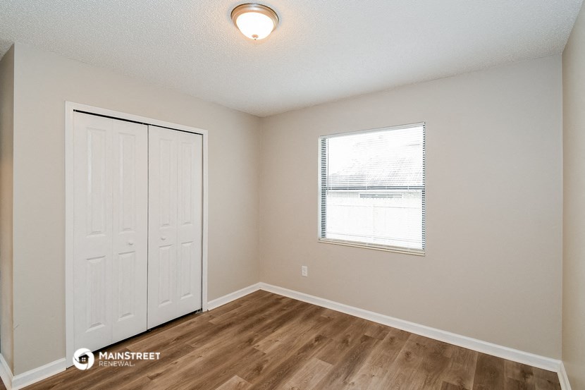 the spacious living room with a door to the closet and a window