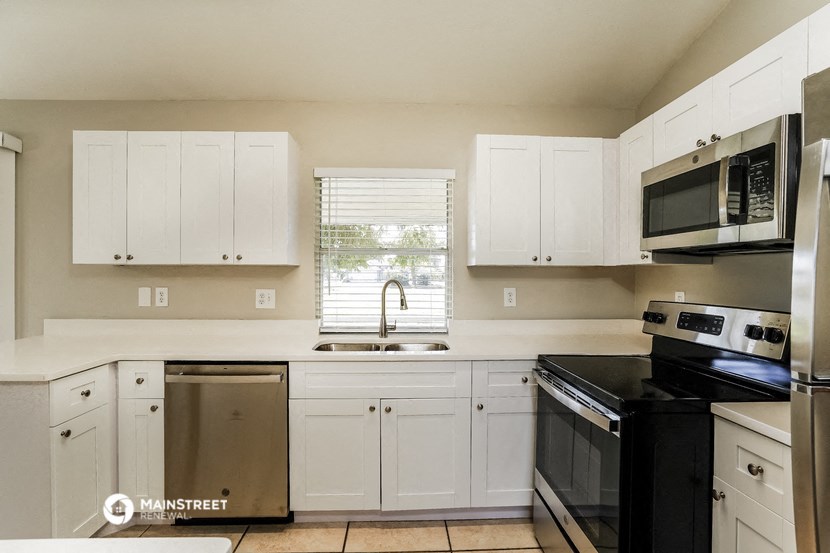 a kitchen with white cabinets and black appliances