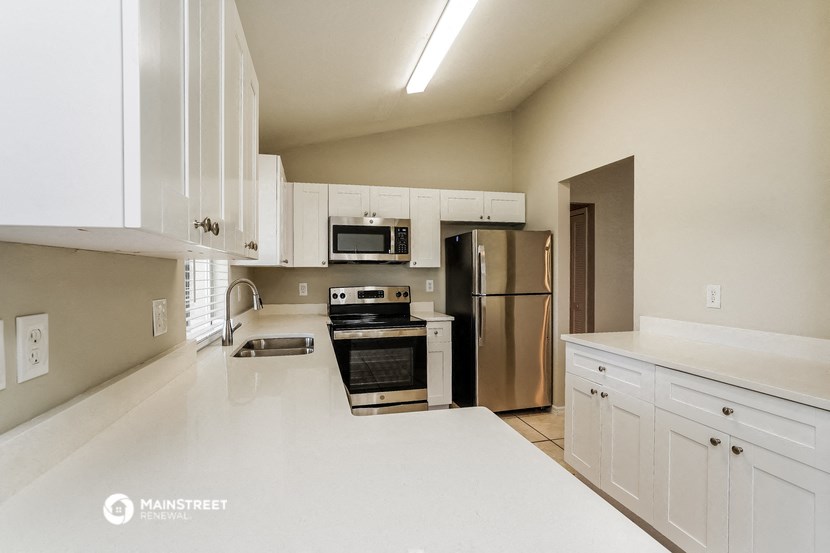 a white kitchen with stainless steel appliances and white counters