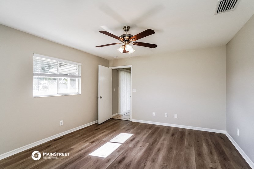 the spacious living room with ceiling fan and wood flooring