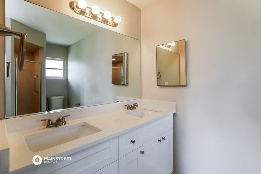 a white bathroom with two sinks and a mirror