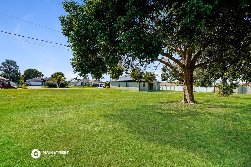 a large yard with a tree and houses in the background