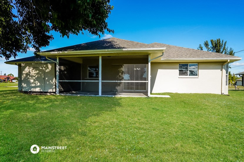 a small white house with a lawn and a tree