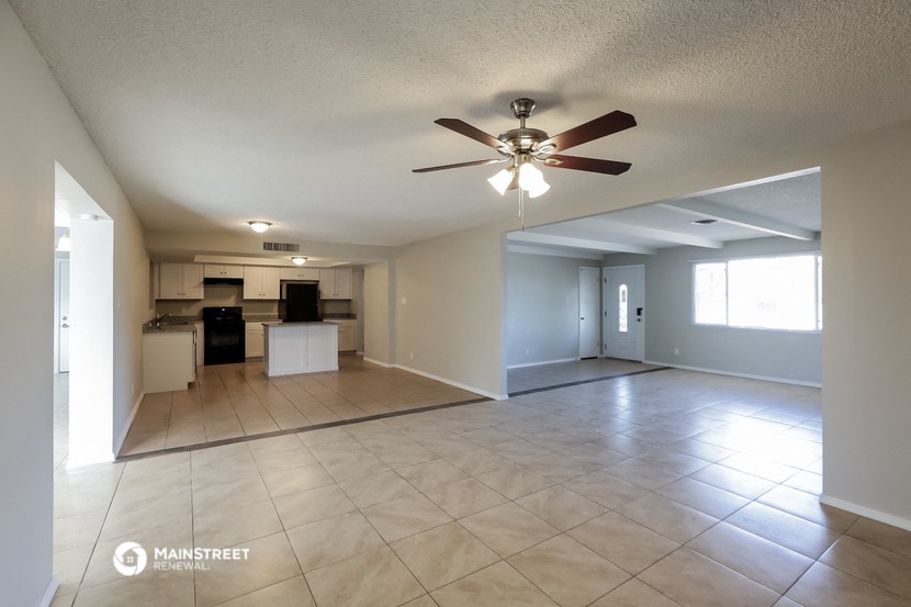 an empty living room and kitchen with a ceiling fan