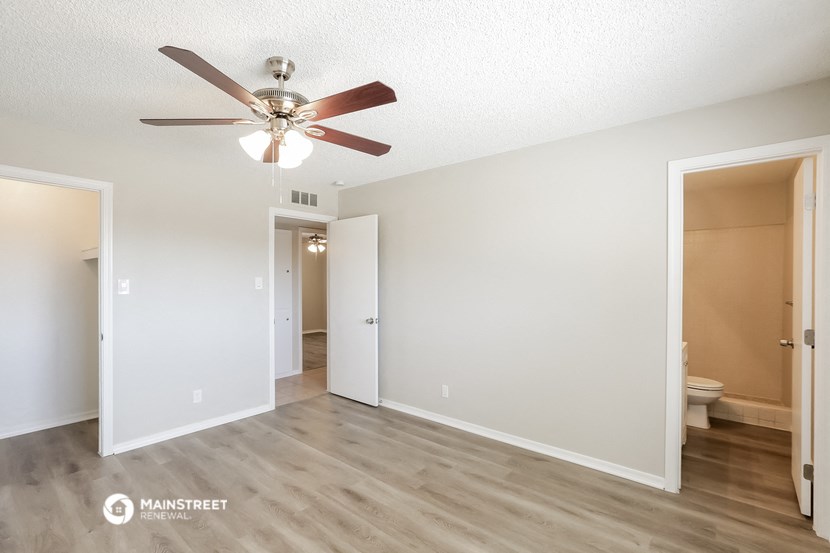 a spacious living room with white walls and a ceiling fan