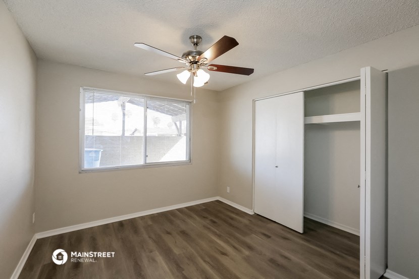 the spacious living room with ceiling fan and closet