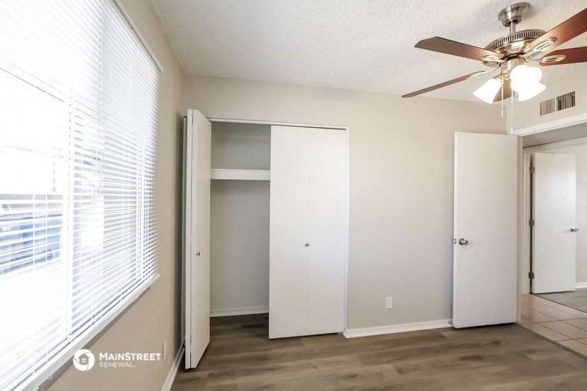 an empty living room with a ceiling fan and a closet