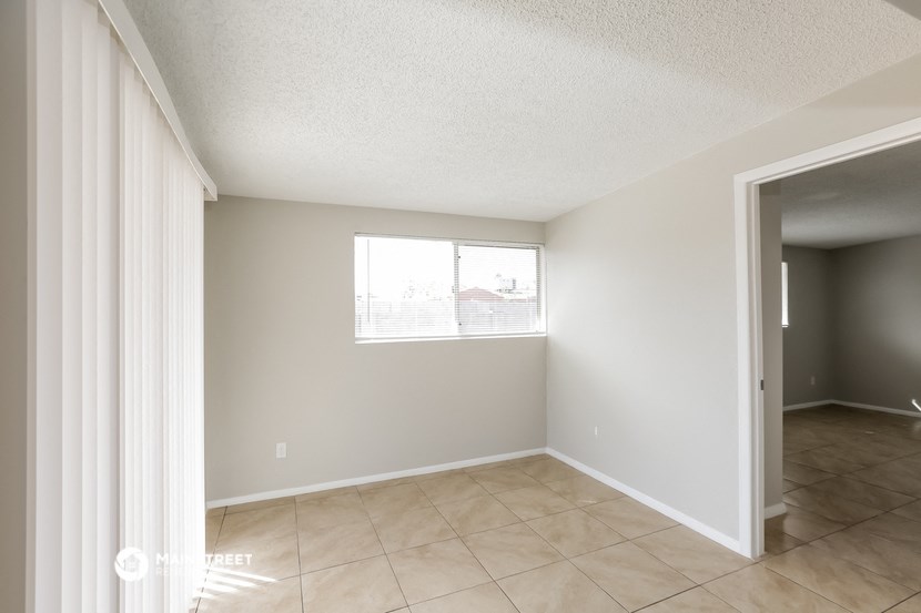 an empty living room with a window and a tiled floor