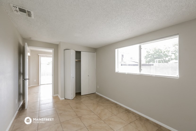 a spacious living room with a large window and a tiled floor