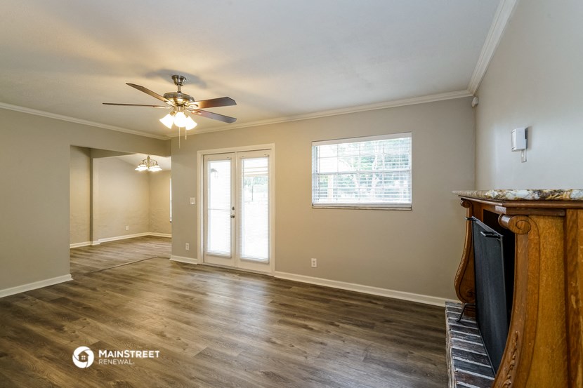 an empty living room with a fireplace and a ceiling fan