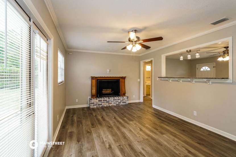 an empty living room with a fireplace and a ceiling fan
