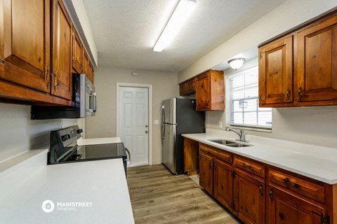 a kitchen with wooden cabinets and a white counter top and a refrigerator