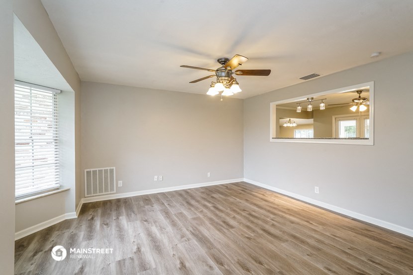 the spacious living room with wood flooring and a ceiling fan