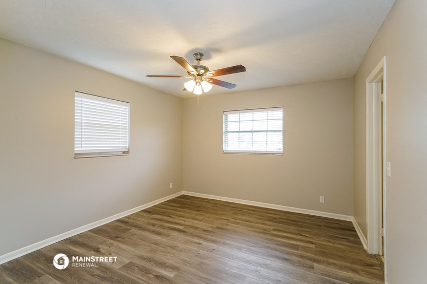 the spacious living room with hardwood floors and a ceiling fan