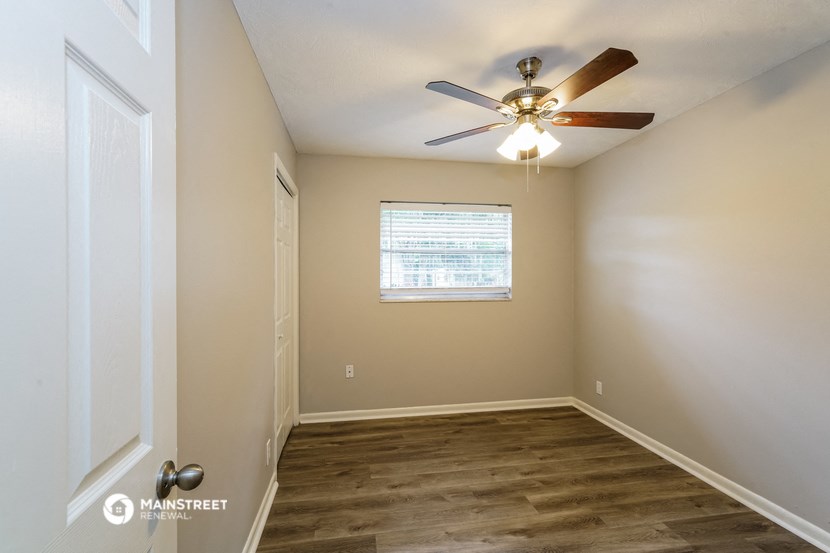 an empty room with a ceiling fan and a window