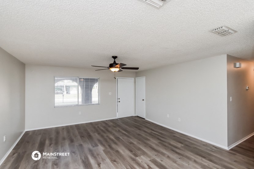 an empty living room with a ceiling fan and a window