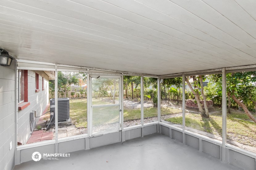 a screened in porch with glass windows overlooking a yard