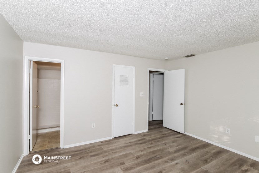a spacious living room with white walls and wood flooring