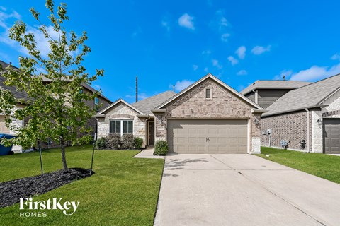 a single story home with a garage and a tree in the yard