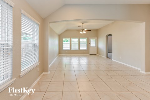 an empty living room with large windows and a tiled floor