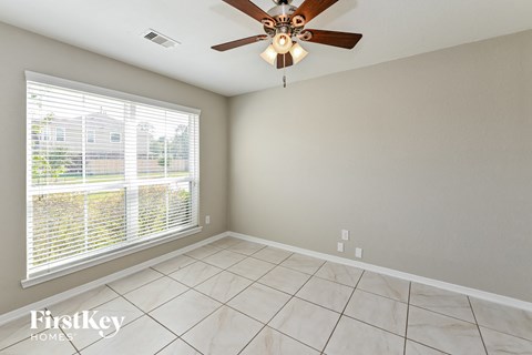 the living room has a large window and a ceiling fan