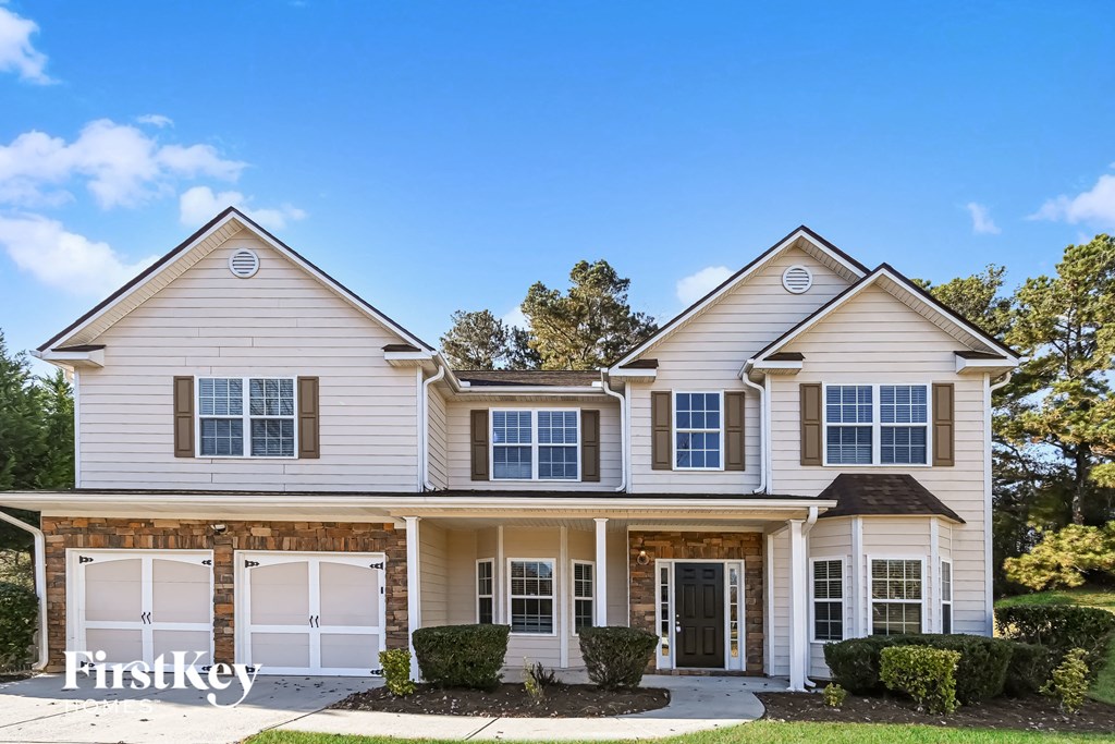 A two-story house with a white exterior and a large front yard.