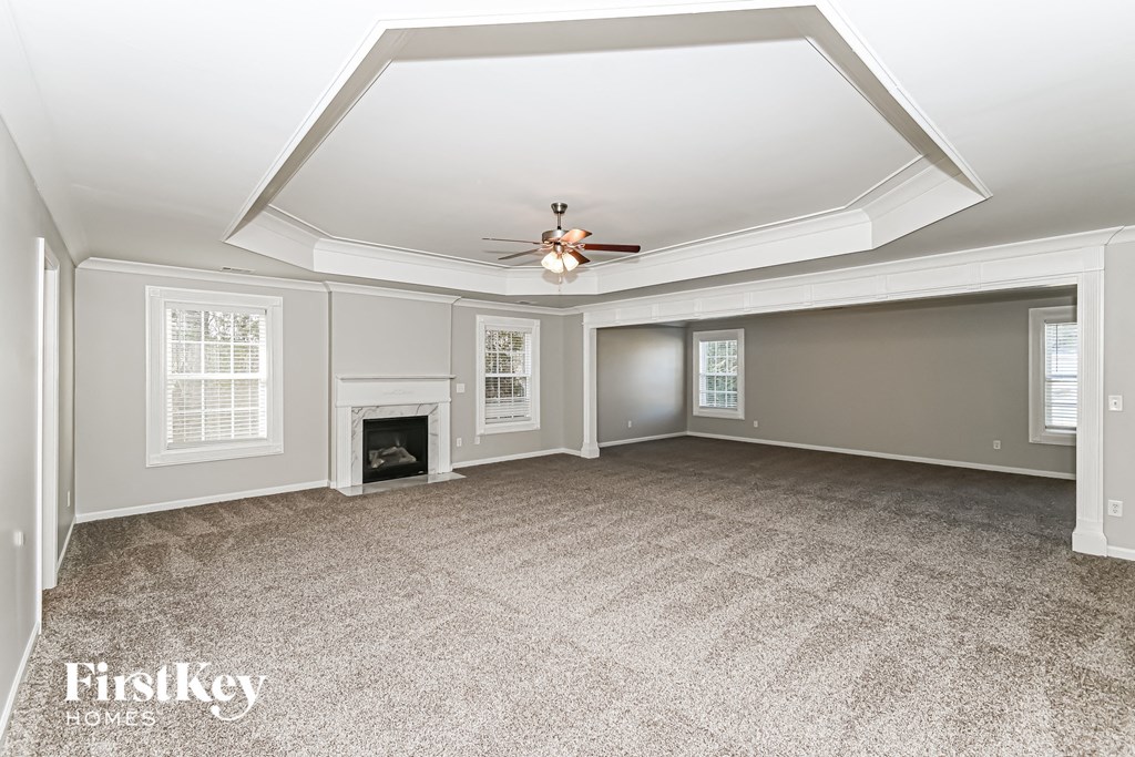 A spacious room with a fireplace and a ceiling fan.