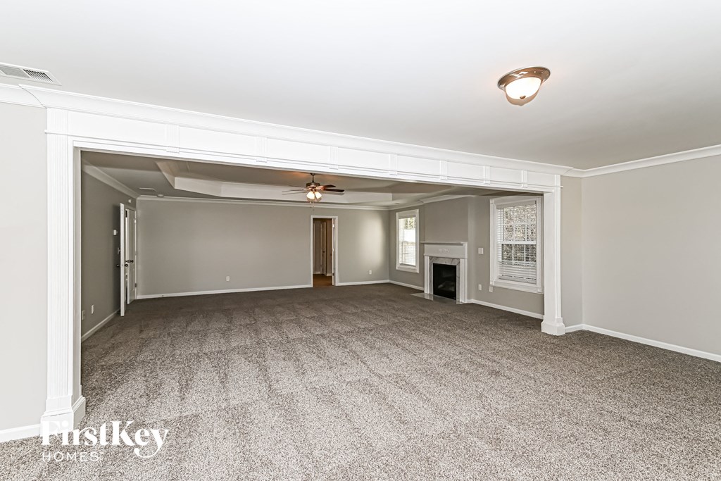 A spacious room with a carpeted floor and a ceiling fan.