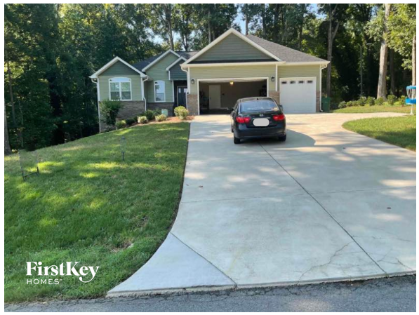 A black car is parked in front of a house with a FirstKey Homes logo.