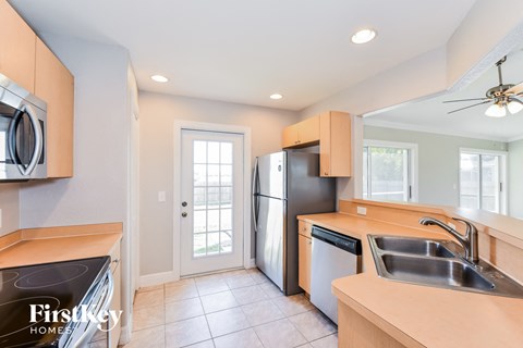 A kitchen with a sink, refrigerator, and a stove top oven.