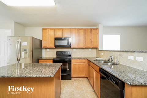 A kitchen with granite countertops and wooden cabinets.