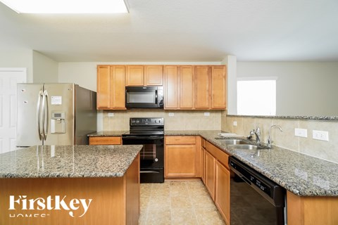 A kitchen with granite countertops and wooden cabinets.