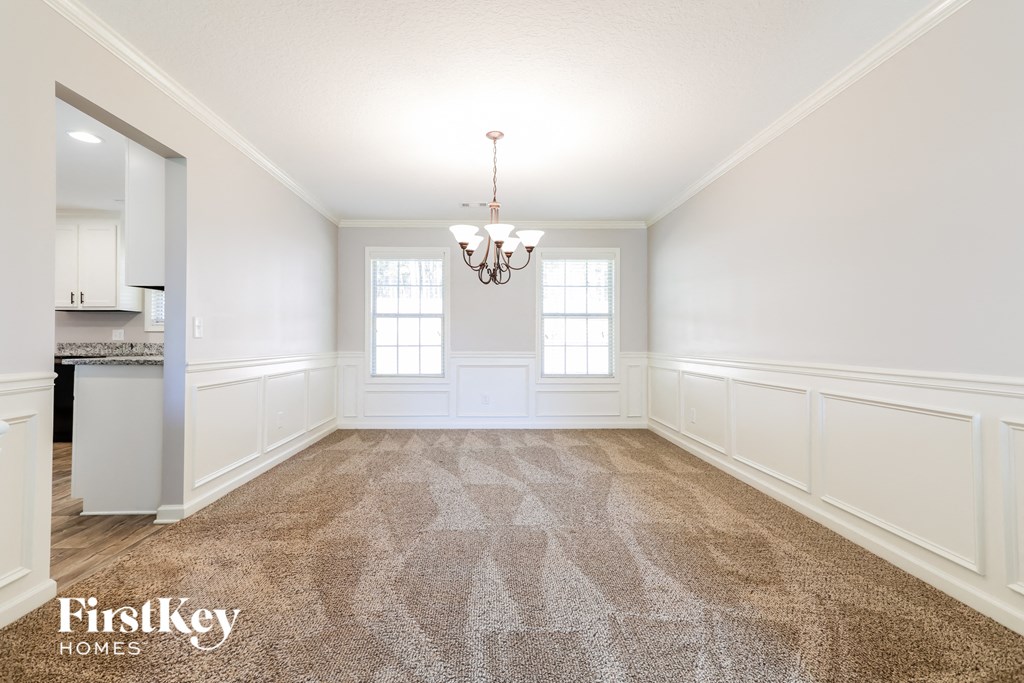 an empty dining room with carpet and white walls