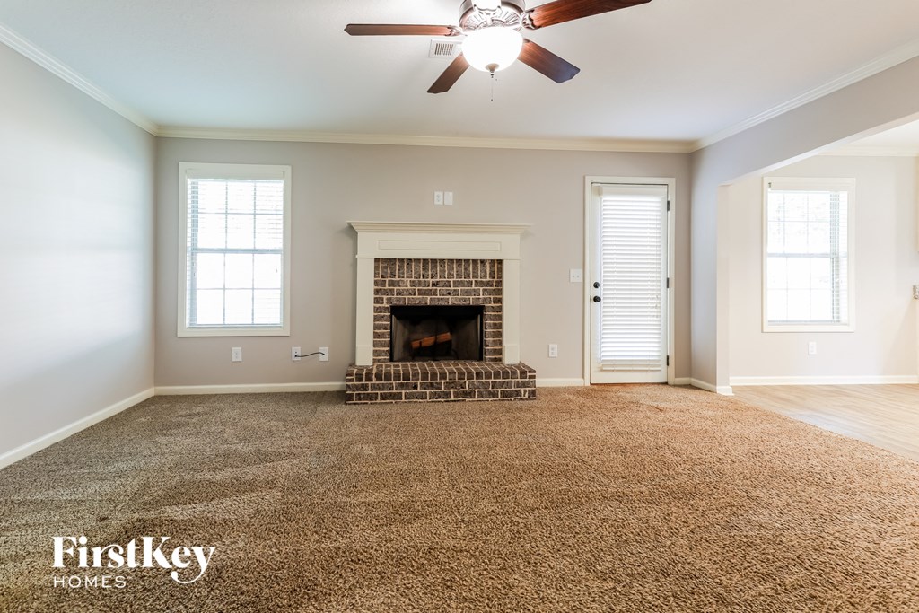 an empty living room with a fireplace and a ceiling fan