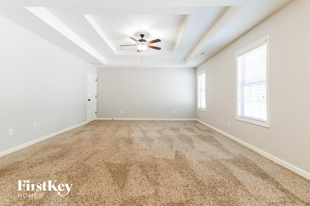 a spacious living room with carpet and a ceiling fan
