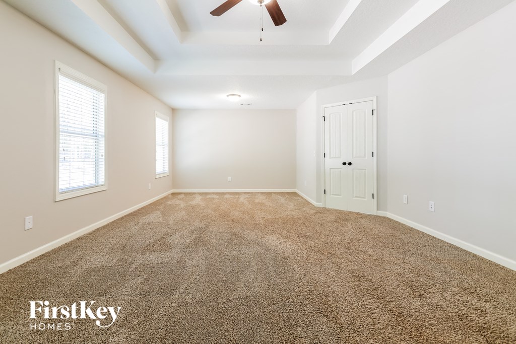 an empty living room with carpet and a ceiling fan