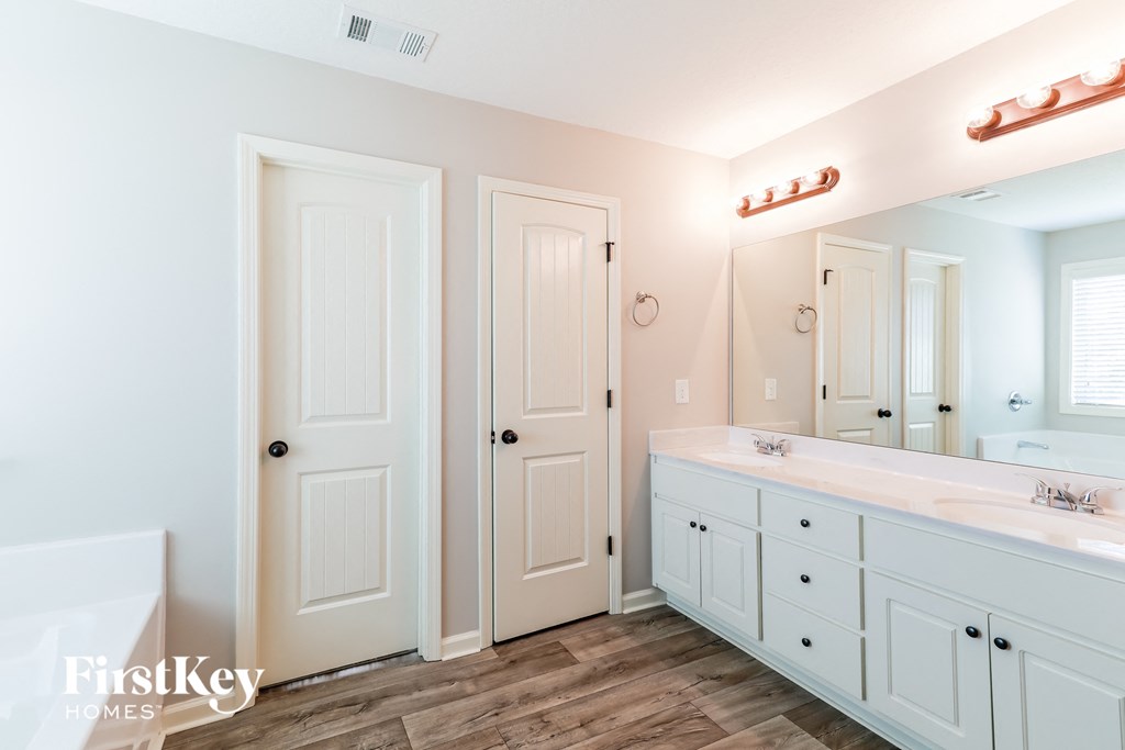 a bathroom with white cabinets and a large mirror