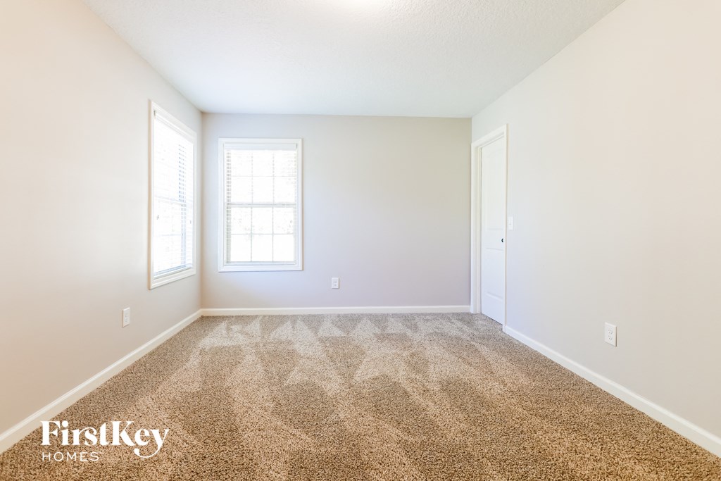 a spacious living room with carpet and white walls