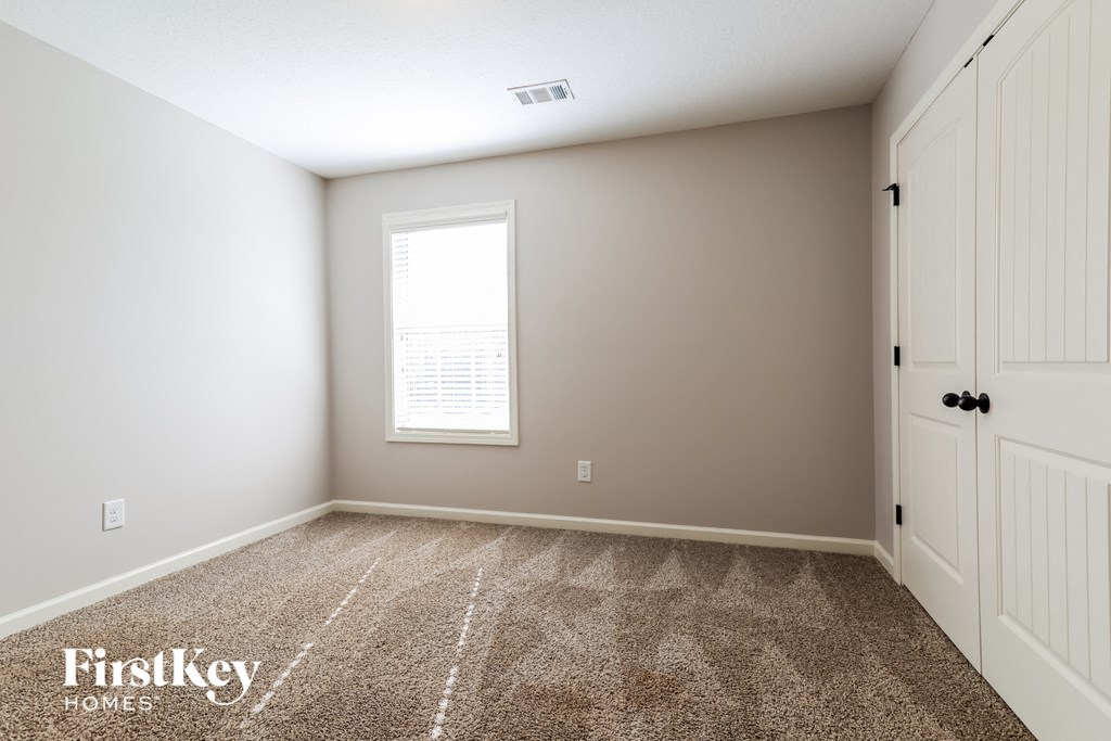 a bedroom with carpet and a window and white doors