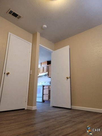 an empty room with an open door to a kitchen