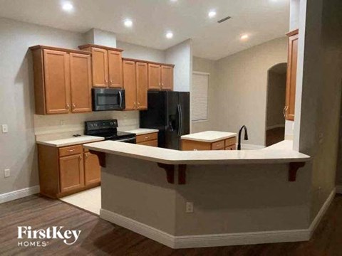 A kitchen with wooden cabinets and a black refrigerator.