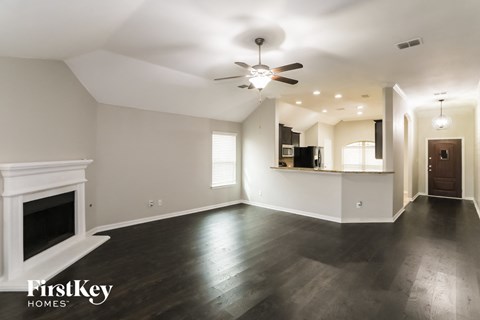 A spacious living room with a fireplace and a ceiling fan.