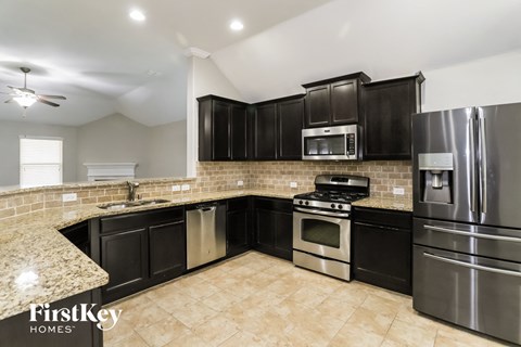 A kitchen with black cabinets and stainless steel appliances.