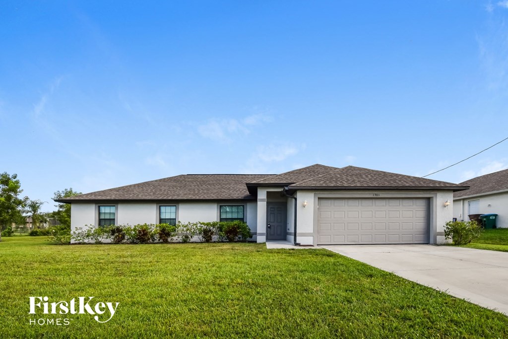 A house with a garage door and a lawn in front.