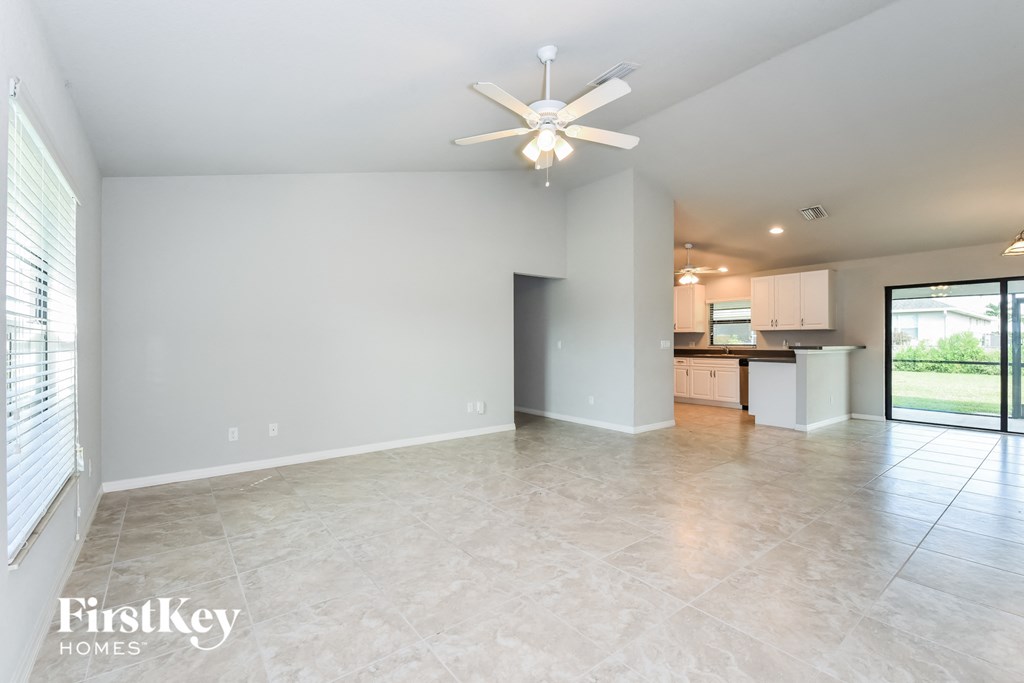 A spacious empty room with a ceiling fan and a sliding glass door leading to a backyard.