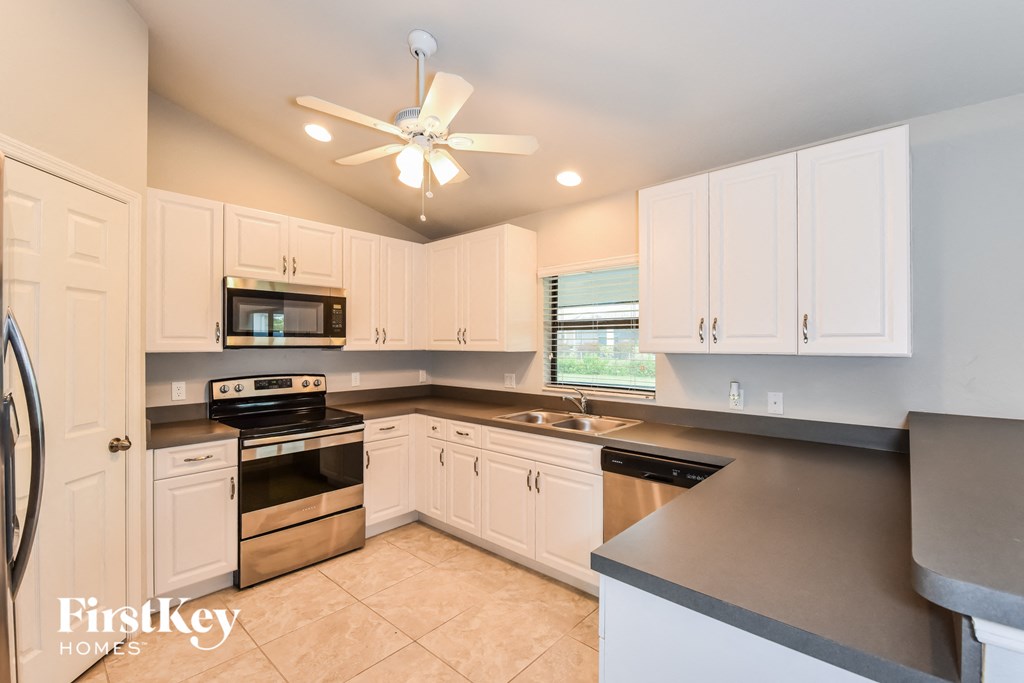 A kitchen with white cabinets and a black countertop.