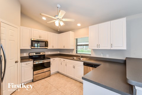 A kitchen with white cabinets and a black countertop.