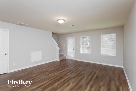 A spacious room with wooden floors and white walls, branded with "FirstKey Homes".